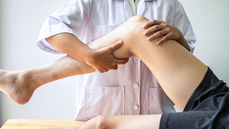 Fizioterapevt izvaja Noblov kompresijski test na pacientovem kolenu, da bi diagnosticiral iliotibialni sindrom (tekaško koleno).